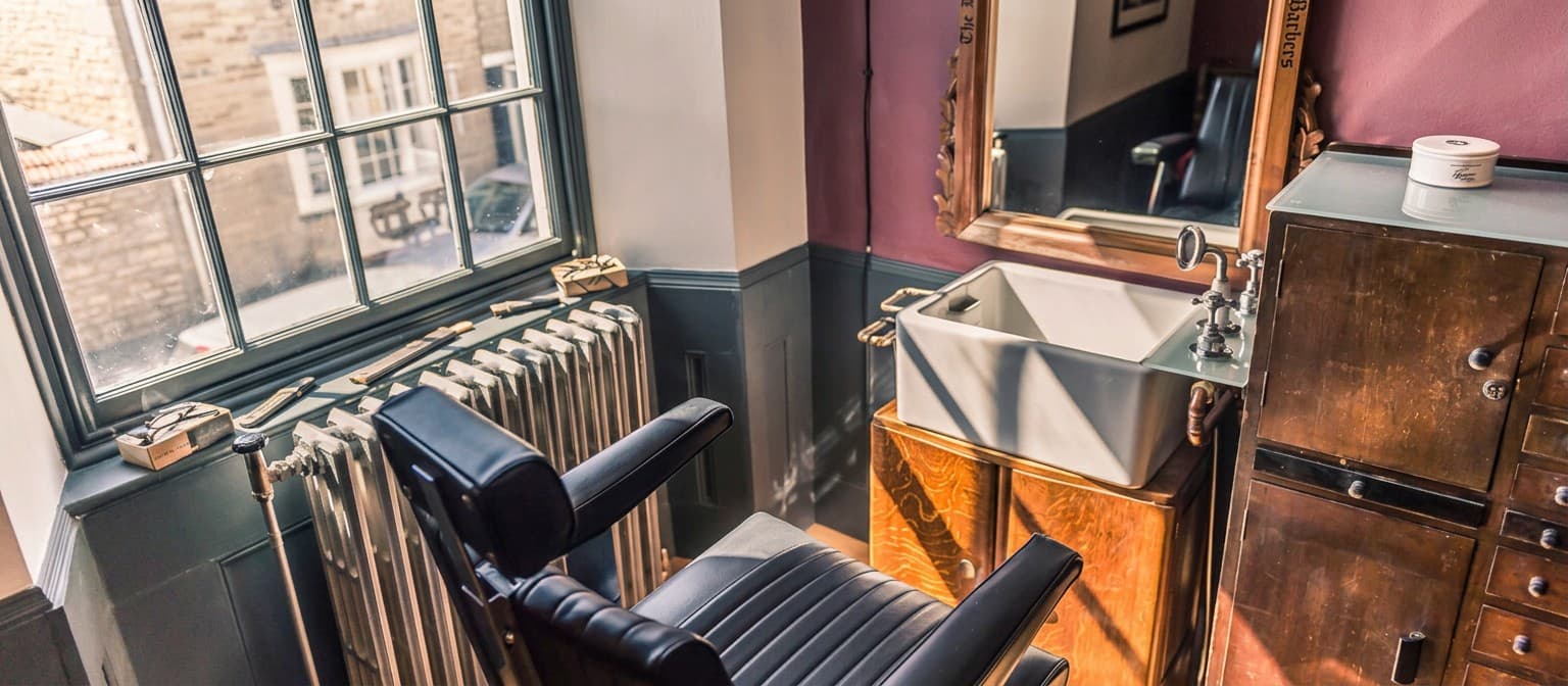 A barber chair and a basin by a sash window